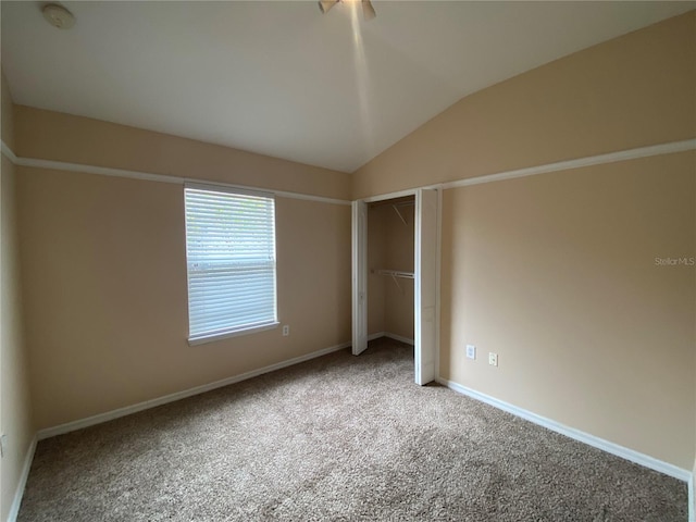 unfurnished bedroom featuring carpet, a closet, ceiling fan, and lofted ceiling