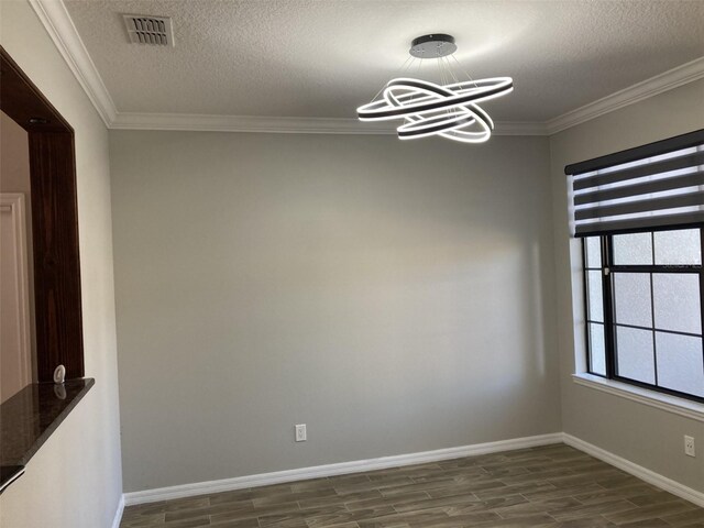 spare room featuring dark wood-style flooring, visible vents, a chandelier, and crown molding