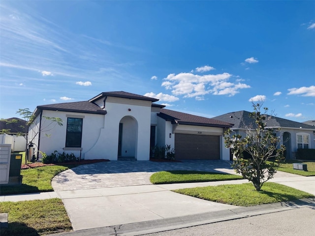 mediterranean / spanish-style home featuring a front lawn, decorative driveway, an attached garage, and stucco siding