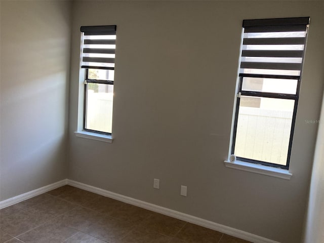 spare room with baseboards and tile patterned floors