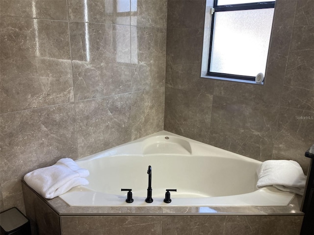 bathroom with a tub to relax in and tile walls