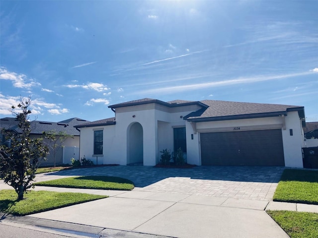 mediterranean / spanish house with a garage, a front yard, decorative driveway, and stucco siding