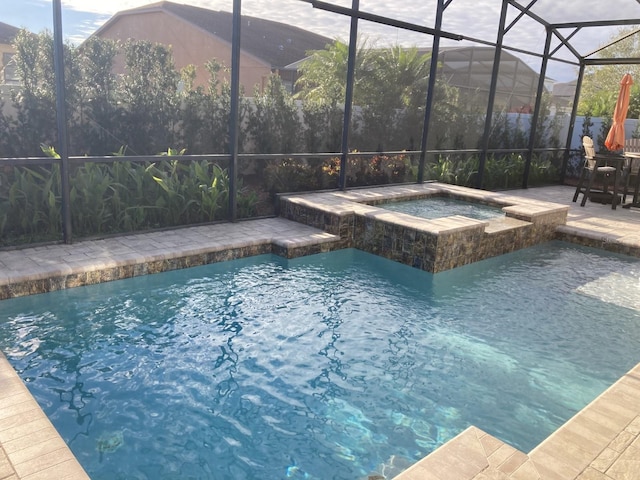 view of pool with a patio area, glass enclosure, and a pool with connected hot tub