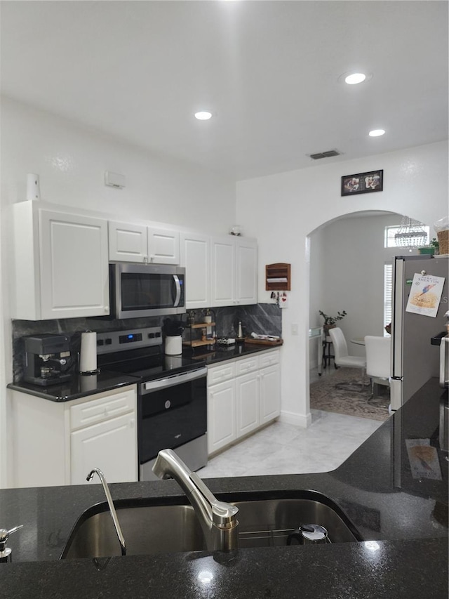 kitchen with backsplash, white cabinetry, sink, and stainless steel appliances