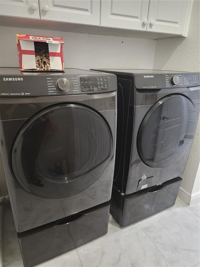 laundry area with independent washer and dryer and cabinets