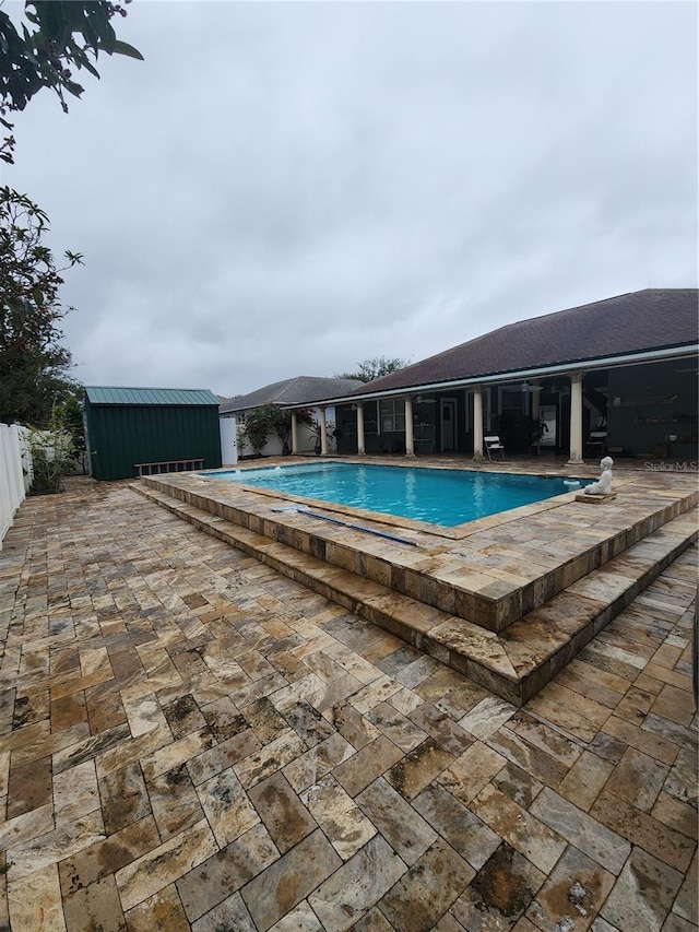 view of swimming pool with a storage unit and a patio