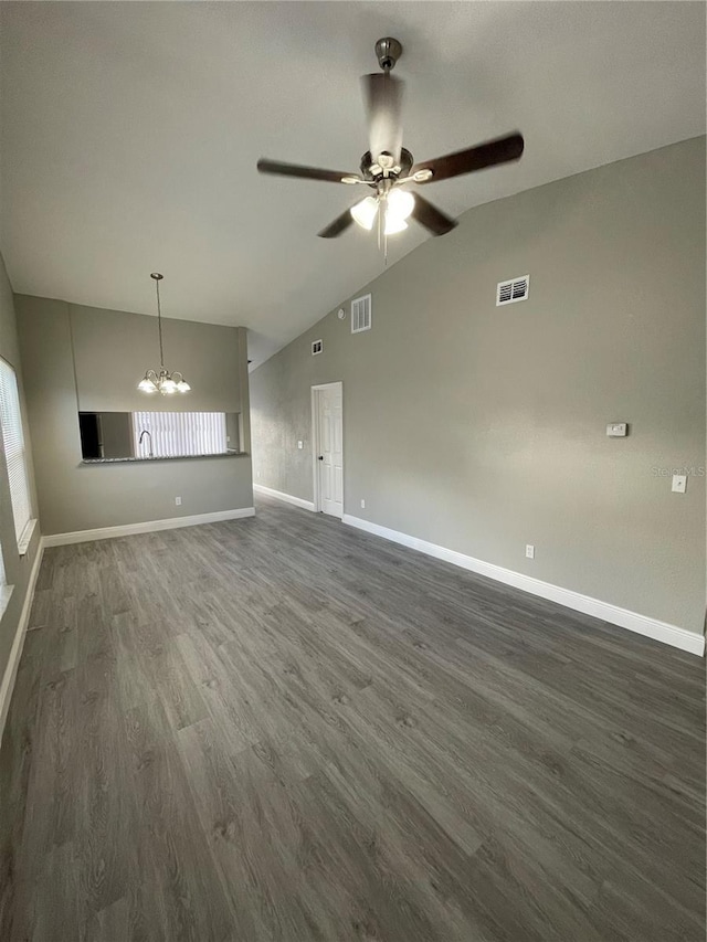 unfurnished living room featuring ceiling fan with notable chandelier, lofted ceiling, and dark wood-type flooring