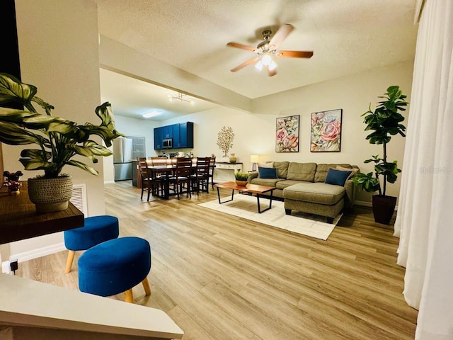 living room with ceiling fan, light hardwood / wood-style floors, and a textured ceiling