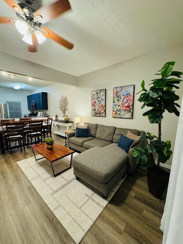 living room with ceiling fan, a textured ceiling, and hardwood / wood-style flooring