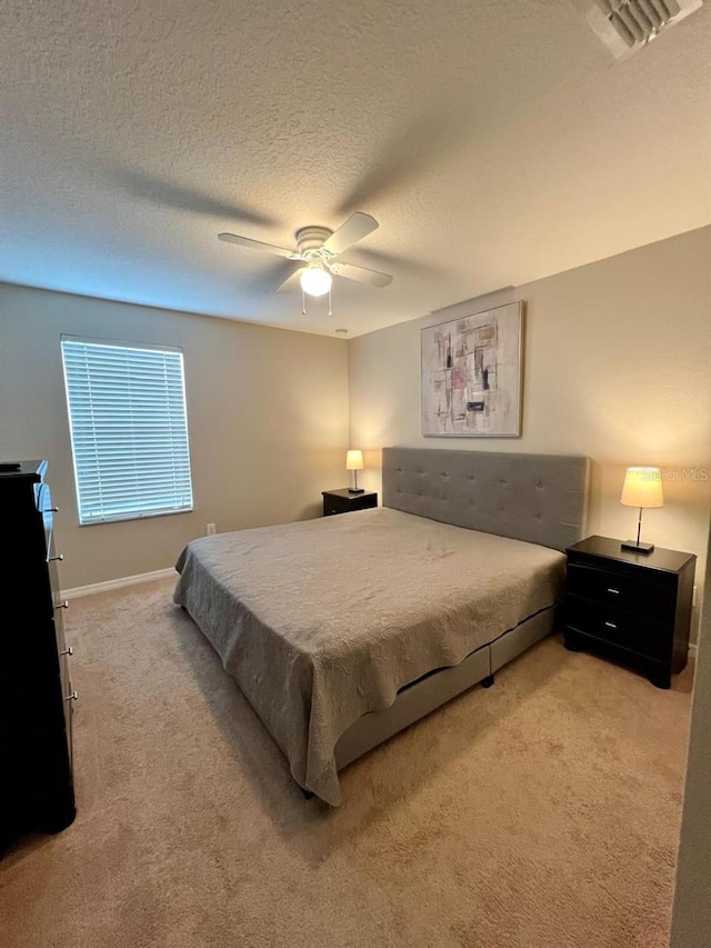 bedroom with a textured ceiling, ceiling fan, and light carpet