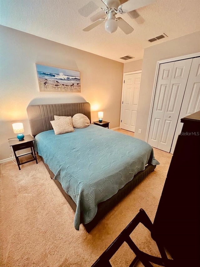 carpeted bedroom featuring ceiling fan, a textured ceiling, and a closet