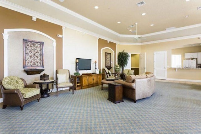 living room featuring carpet flooring, ceiling fan, a raised ceiling, decorative columns, and ornamental molding