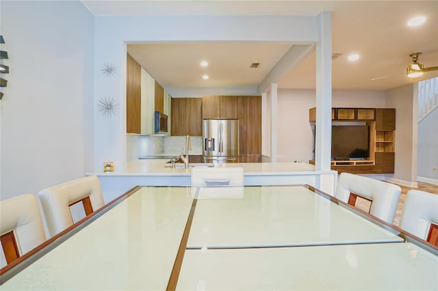 kitchen with ceiling fan, sink, a kitchen breakfast bar, kitchen peninsula, and appliances with stainless steel finishes