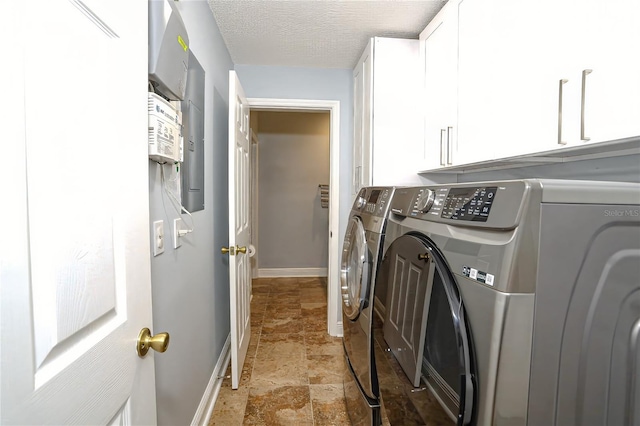 clothes washing area featuring cabinets, washing machine and dryer, and a textured ceiling