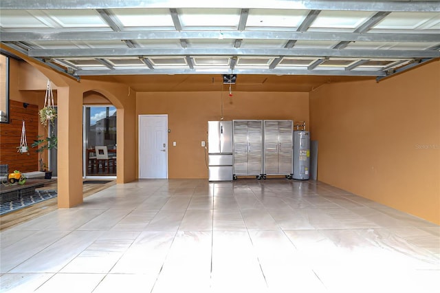 garage featuring stainless steel refrigerator, water heater, and a garage door opener