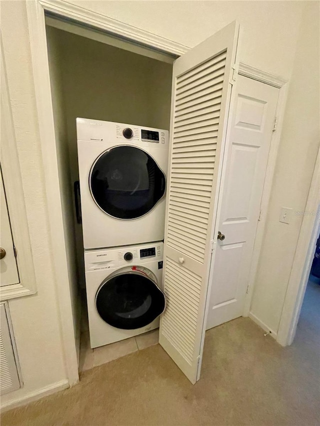 clothes washing area with light colored carpet and stacked washing maching and dryer