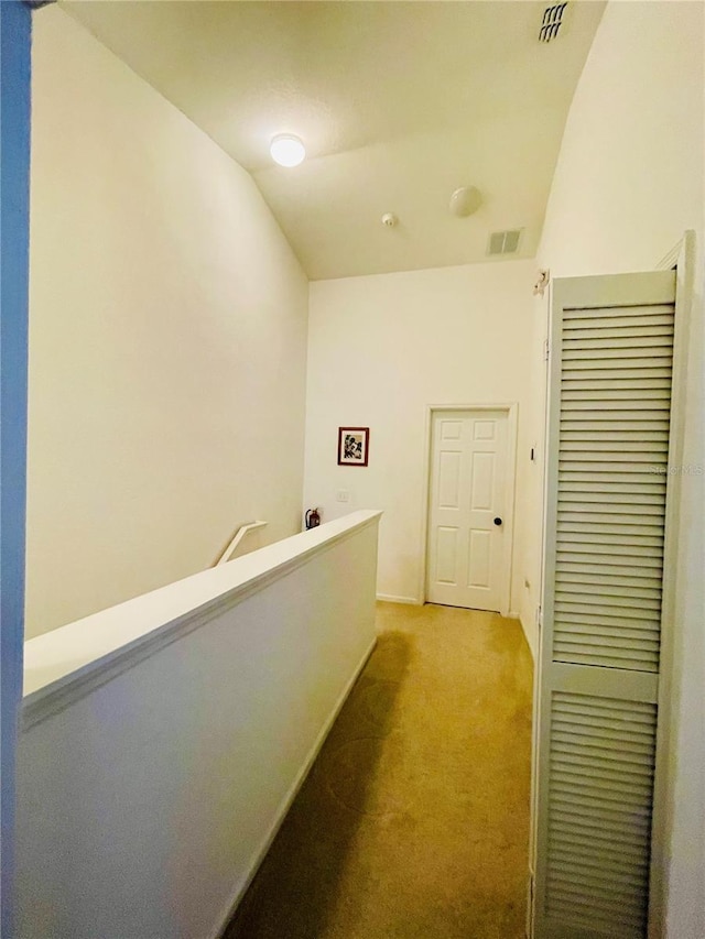 hallway with carpet floors and vaulted ceiling