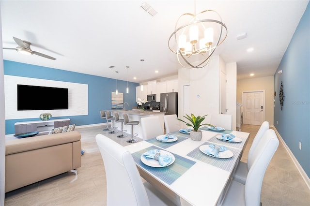 dining room featuring sink and ceiling fan with notable chandelier