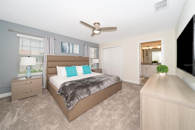 bedroom with connected bathroom, ceiling fan, a closet, and light carpet