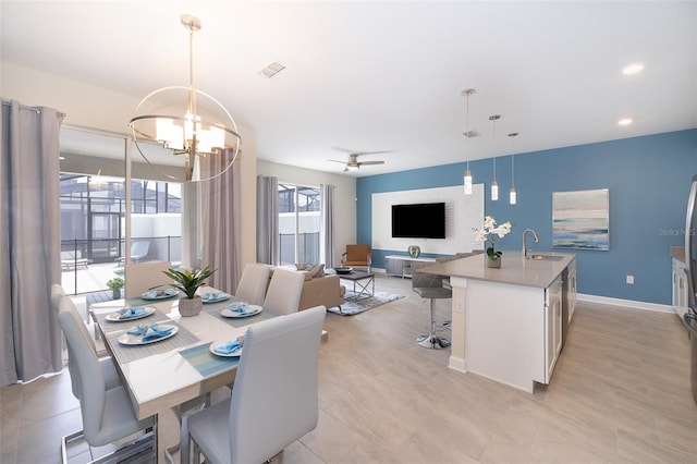 dining space featuring plenty of natural light, light hardwood / wood-style flooring, ceiling fan with notable chandelier, and sink