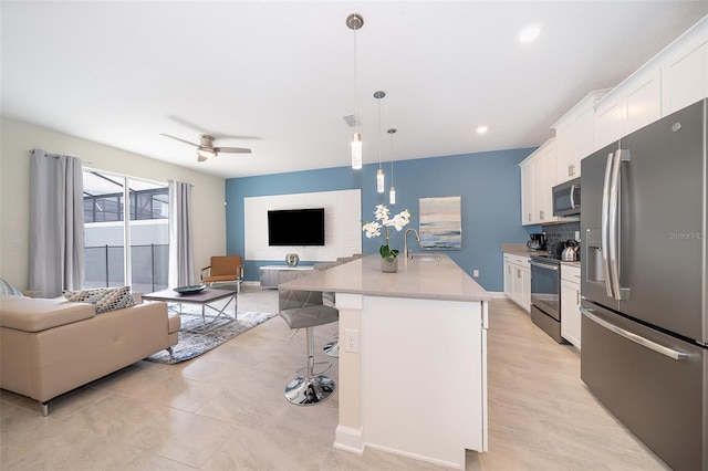 kitchen featuring pendant lighting, sink, an island with sink, appliances with stainless steel finishes, and white cabinetry