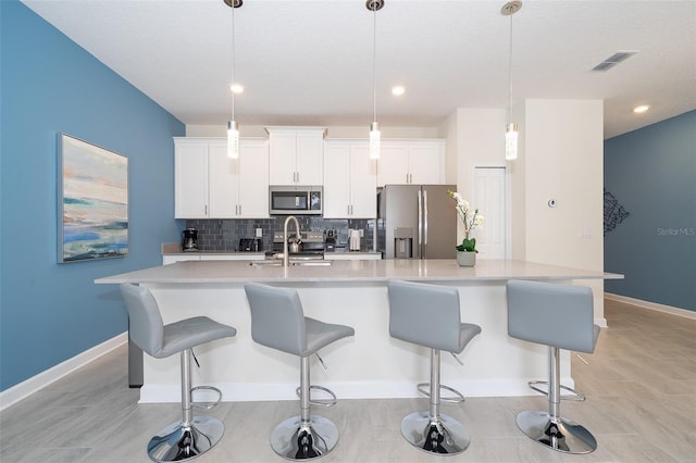 kitchen featuring white cabinets, decorative light fixtures, stainless steel appliances, and a spacious island