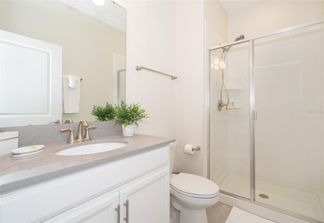 bathroom featuring vanity, toilet, and a shower with shower door