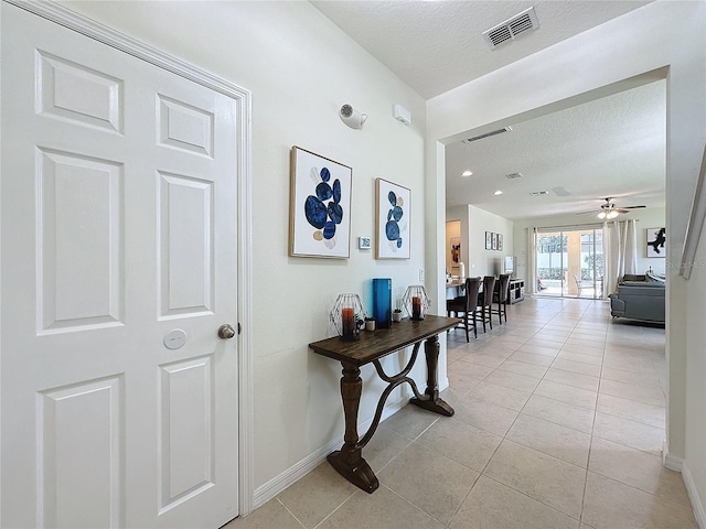 corridor with light tile patterned floors and a textured ceiling