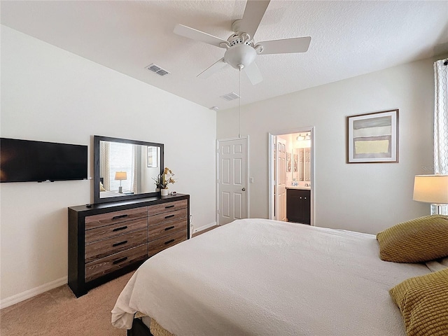 bedroom with ceiling fan, light carpet, and ensuite bathroom