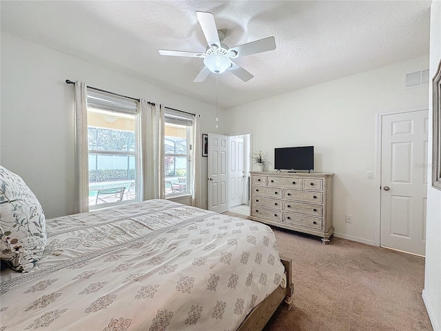 carpeted bedroom featuring ceiling fan and a textured ceiling