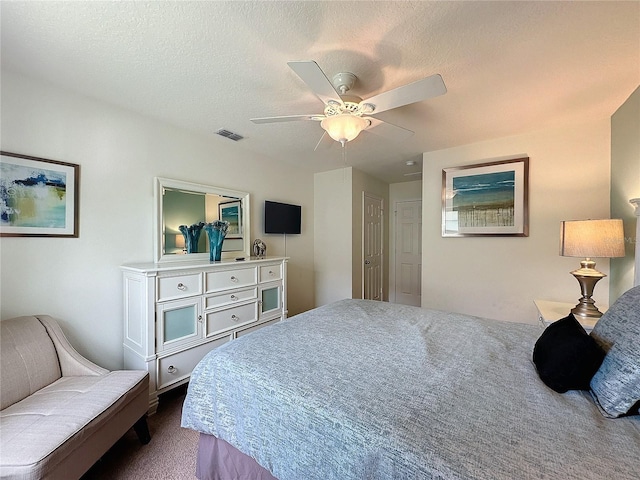 carpeted bedroom featuring ceiling fan and a textured ceiling