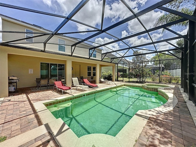 view of pool featuring a patio area, glass enclosure, and an in ground hot tub