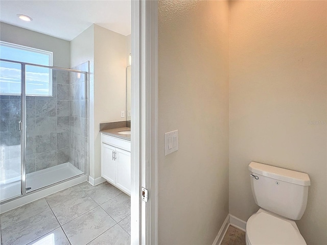 bathroom featuring tile patterned floors, vanity, a shower with shower door, and toilet