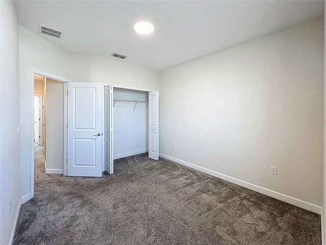 unfurnished bedroom with dark carpet and a closet