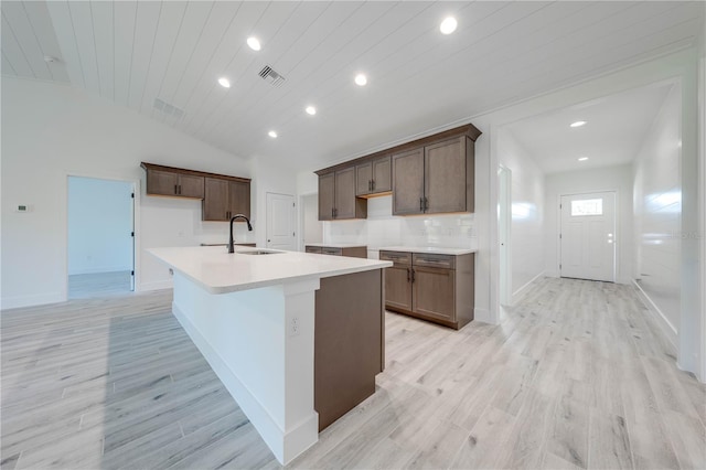 kitchen with wood ceiling, a center island with sink, tasteful backsplash, light wood-type flooring, and sink