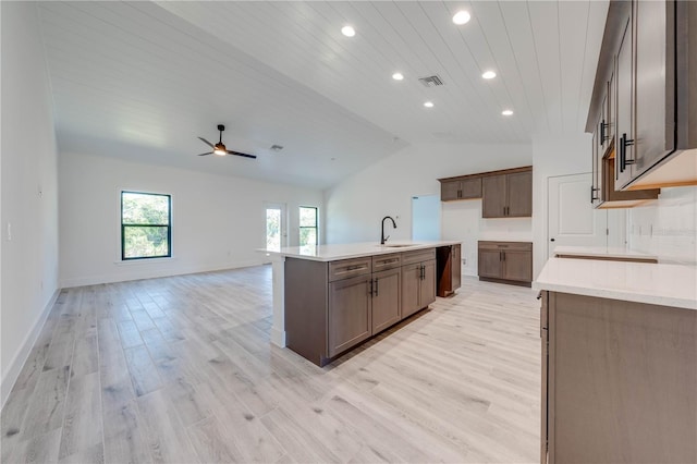 kitchen featuring lofted ceiling, an island with sink, light hardwood / wood-style floors, sink, and ceiling fan