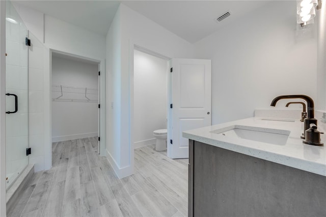 bathroom featuring toilet, a shower with door, hardwood / wood-style flooring, and vanity