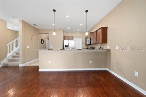 kitchen with kitchen peninsula, stainless steel appliances, dark hardwood / wood-style flooring, and hanging light fixtures