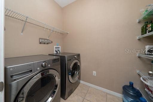 laundry area featuring washer and clothes dryer and light tile patterned floors