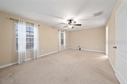 carpeted empty room featuring ceiling fan and a wealth of natural light