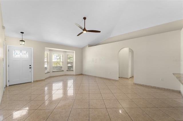 unfurnished living room with ceiling fan, vaulted ceiling, and light tile patterned flooring