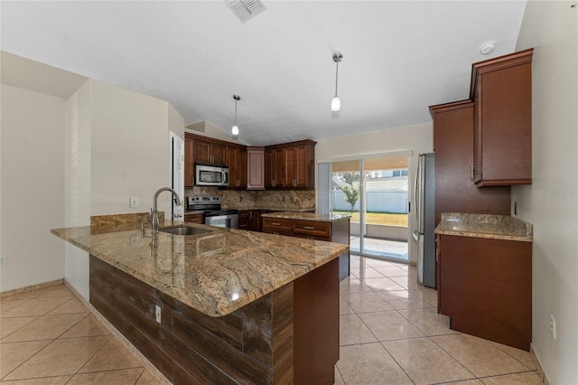 kitchen with pendant lighting, kitchen peninsula, sink, light stone countertops, and appliances with stainless steel finishes