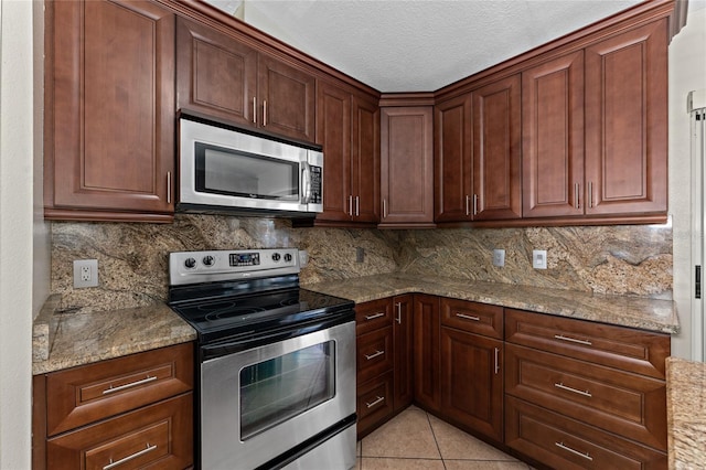 kitchen featuring light tile patterned floors, backsplash, appliances with stainless steel finishes, and light stone counters