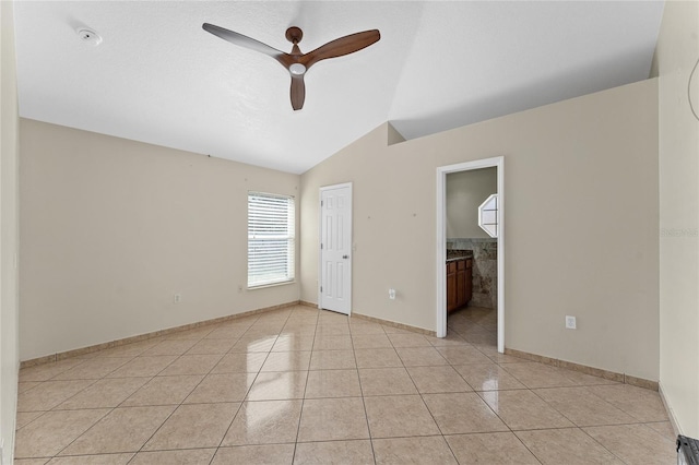 spare room featuring ceiling fan, light tile patterned floors, and vaulted ceiling