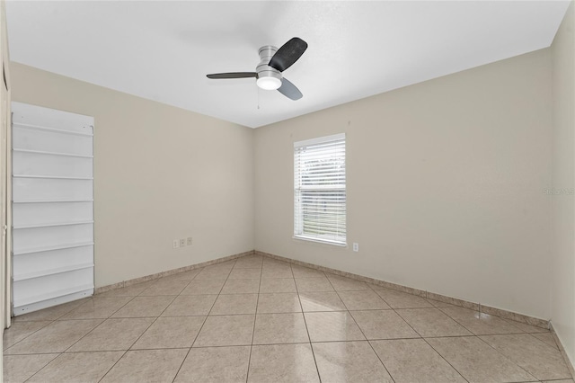 spare room featuring ceiling fan, light tile patterned floors, and built in features