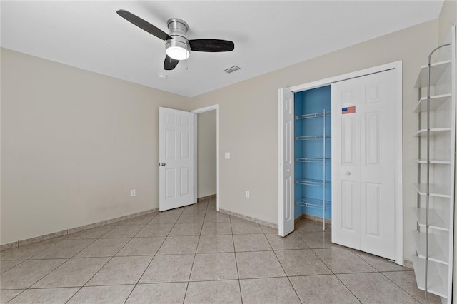 unfurnished bedroom featuring ceiling fan, light tile patterned floors, and a closet