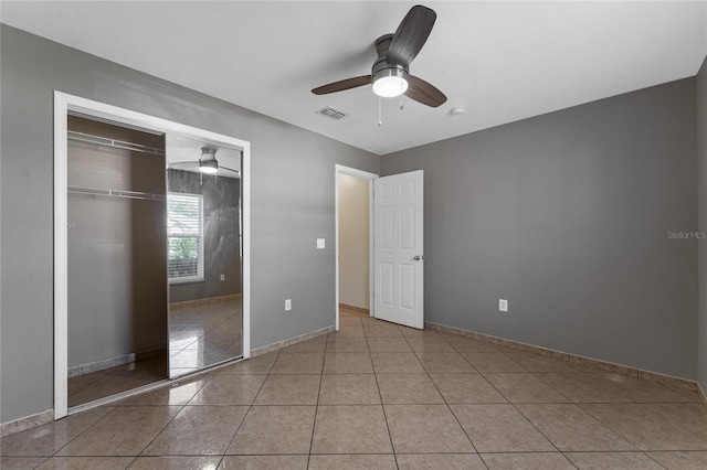 unfurnished bedroom with ceiling fan, light tile patterned floors, and a closet