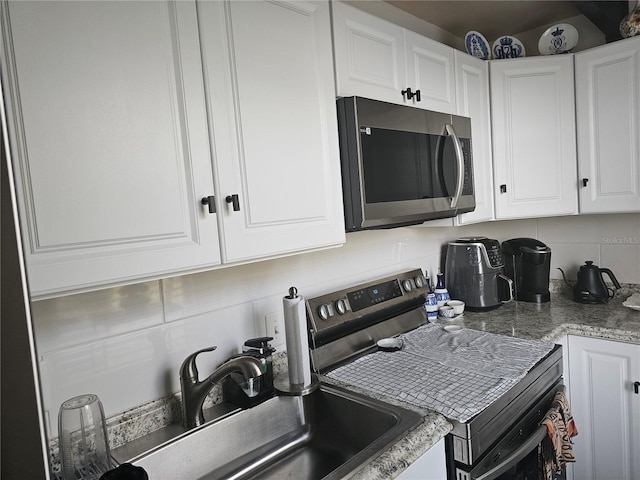 kitchen with stainless steel appliances, tasteful backsplash, and white cabinetry