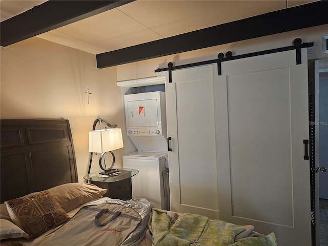 washroom with stacked washer / drying machine and a barn door