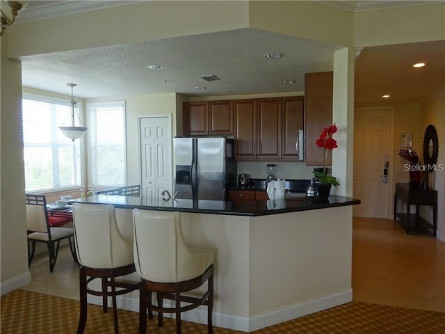 kitchen featuring pendant lighting, appliances with stainless steel finishes, a textured ceiling, a kitchen bar, and crown molding